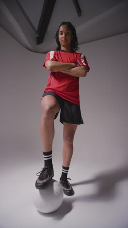 Vertical-Video-Portrait-Of-Female-Footballer-Wearing-Club-Kit-Against-Grey-Vertical-Video-Studio-Background-Controlling-Ball-With-Foot